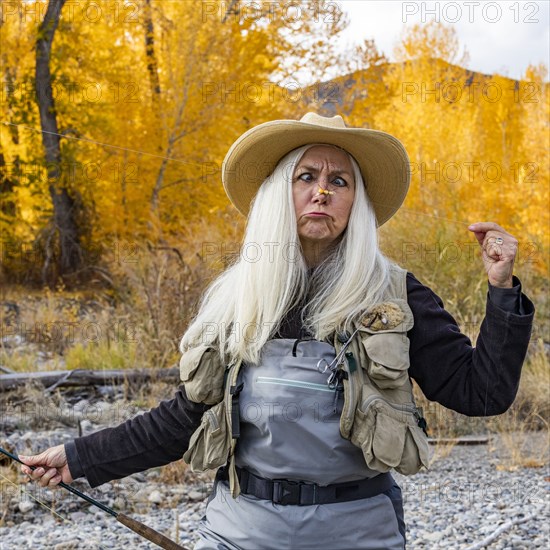 Senior woman holding fishing rod and making faces