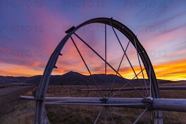 Close-up of irrigation wheel in field at sunset