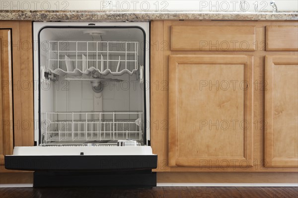 Empty open dishwasher in domestic kitchen