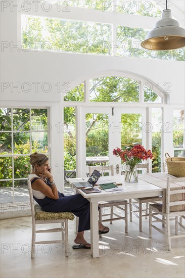 Mature woman with laptop in dining room