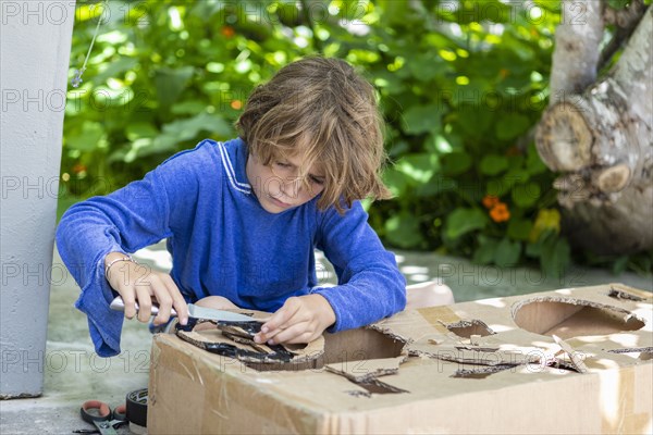 Boy cutting a cardboard box