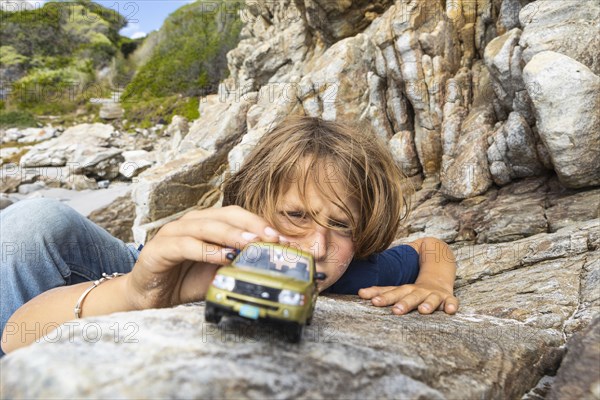 Boy playing outdoors with toy car