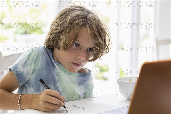 Boy drawing picture during online lesson