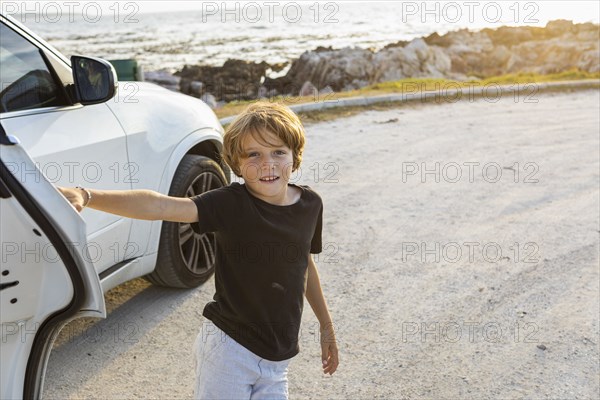 Portrait of Boy leaning on SUV