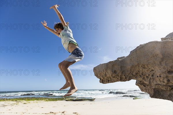 Boy jumping off rock