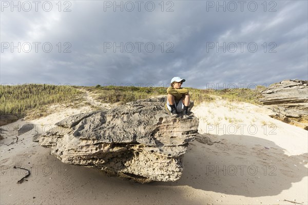 Boy sitting on beach rock