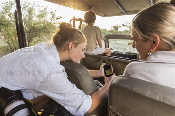 Woman with son (8-9) and daughter (16-17) in safari vehicle