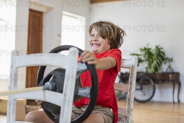 Boy playing with steering wheel in living room