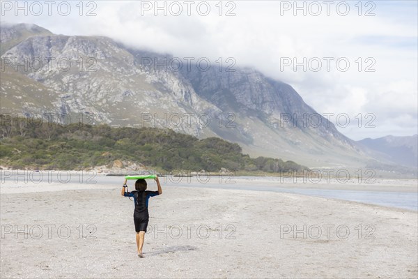 Boy carrying bodyboard on beach
