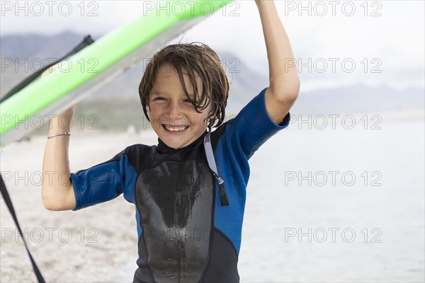 Boy carrying bodyboard on beach