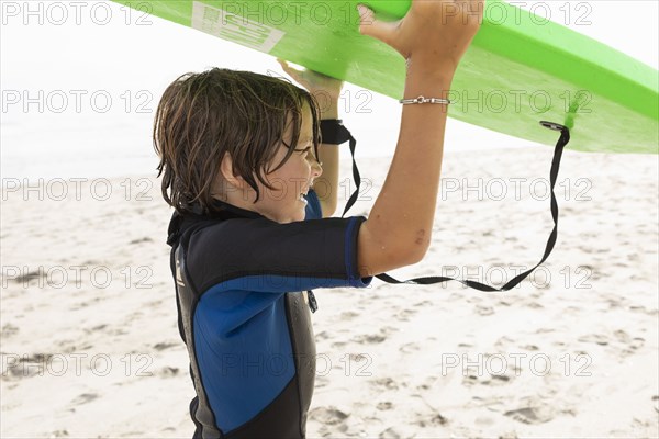 Boy carrying bodyboard on beach