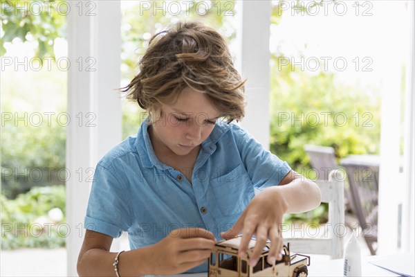 Boy building wooden toy car at home