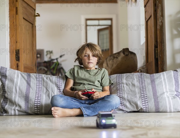 Boy playing with remote-control toy car at home