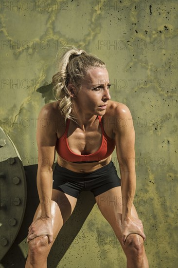 Tired athlete woman leaning against wall