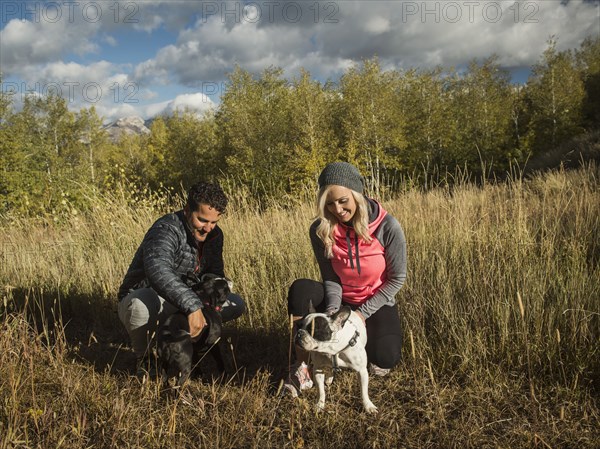 Smiling couple with two dogs in grassy field