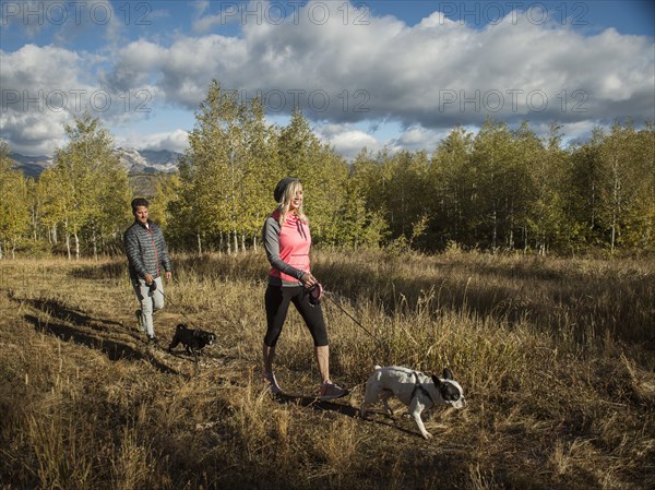 Couple with two dogs walking in grassy field