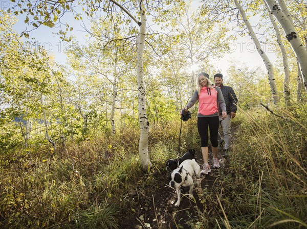 Couple with two dogs walking in forest