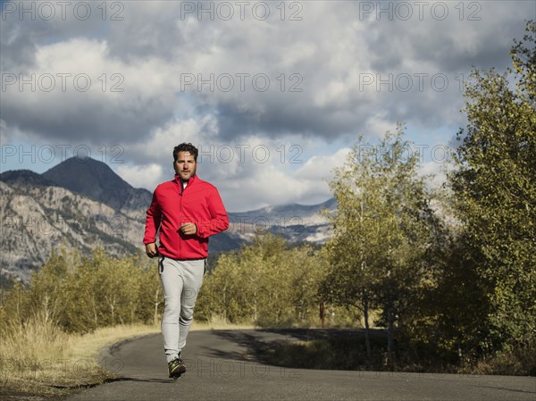 Man jogging on mountain road on sunny day