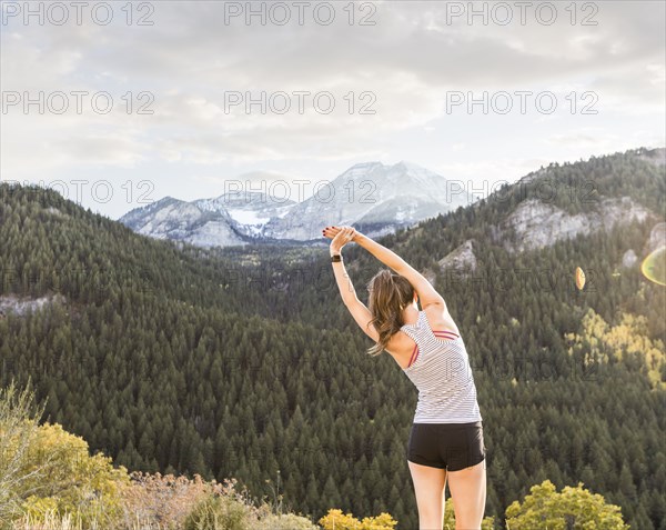 Rear view of woman stretching in mountain landscape