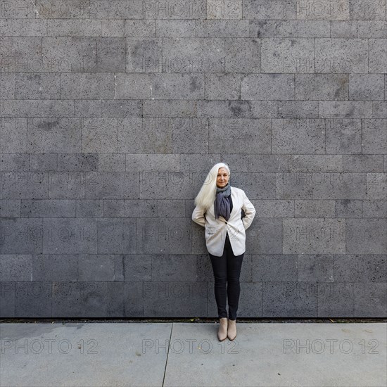 Portrait of senior woman leaning against wall