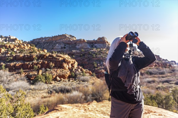 Senior hiker looking through binoculars