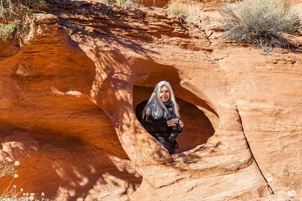 Senior hiker standing in rock opening in sandstone cliff