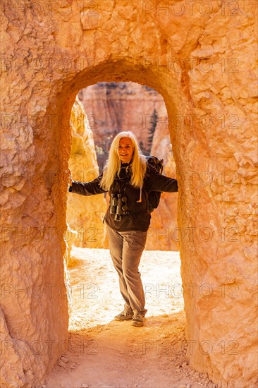 Senior hiker standing in sandstone archway