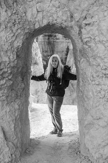 Senior female hiker standing in natural sandstone archway