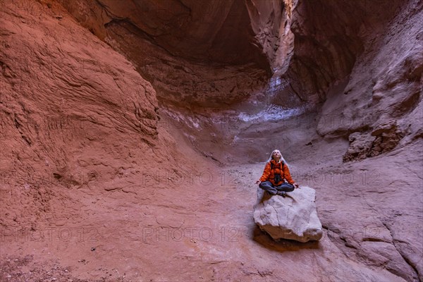 Senior female hiker sitting on rock in canyon