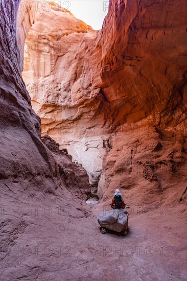 Senior female hiker sitting on rock in canyon