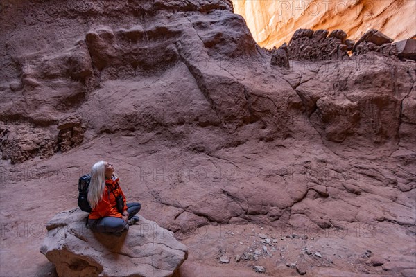 Senior female hiker sitting on rock in canyon