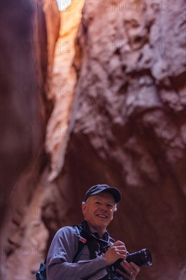 Senior male hiker with camera in canyon