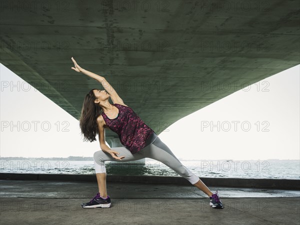 Woman stretching under bridge