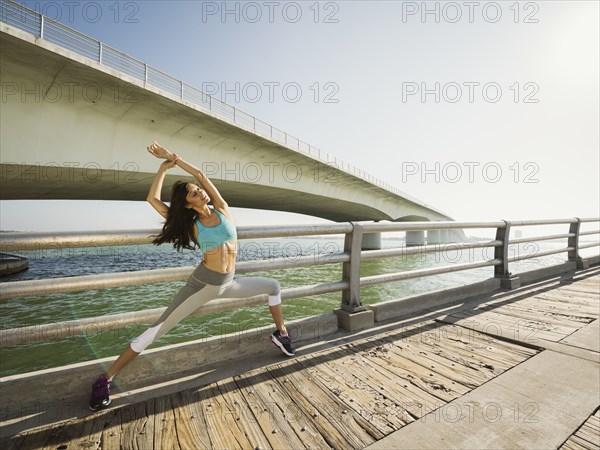 Woman stretching on bridge on sunny day