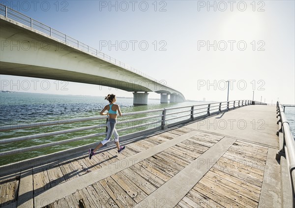Rear view of woman jogging on bridge on sunny day