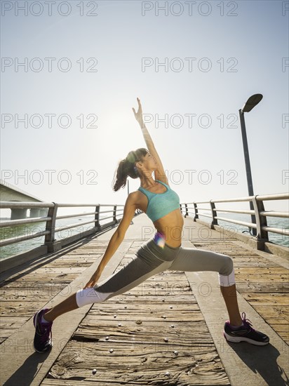 Woman stretching on bridge on sunny day