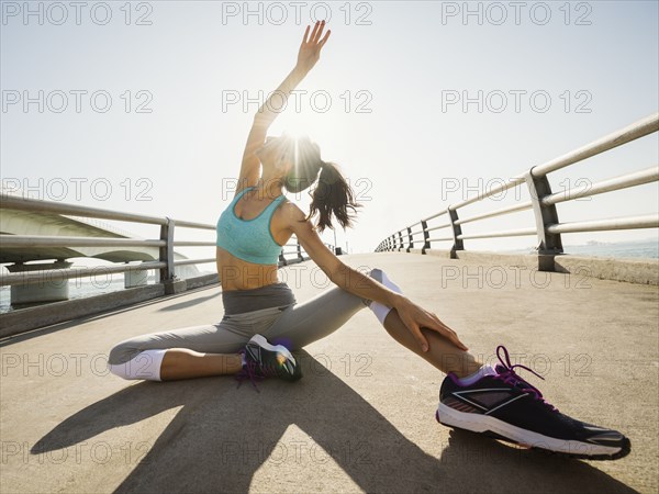 Woman stretching on bridge on sunny day
