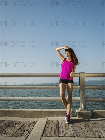 Woman in sport clothing standing on bridge on sunny day