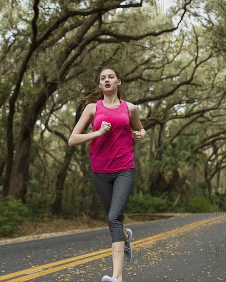 Woman jogging on treelined country road