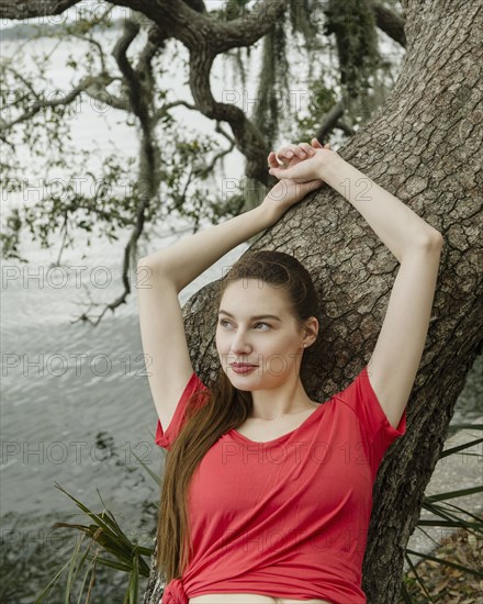 Smiling woman leaning against tree trunk