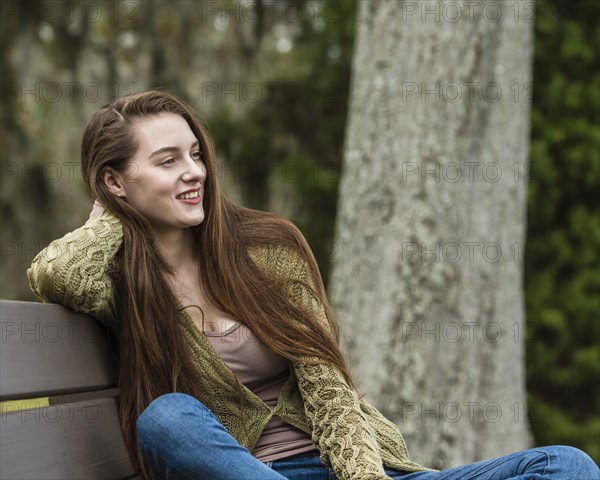 Smiling woman sitting on bench in park