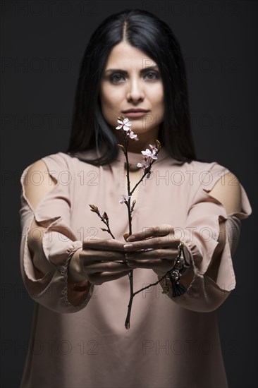 Studio portrait of woman holding blooming twig