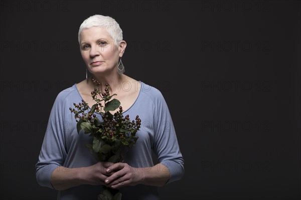 Studio portrait of woman in blue shirt holding bunch of flowers