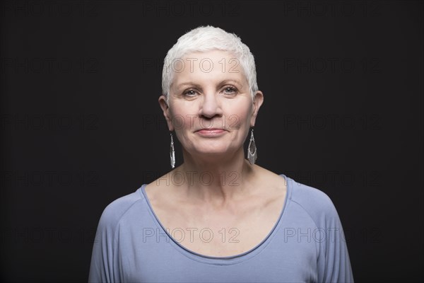 Studio portrait of smiling woman with white short hair