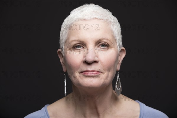 Studio portrait of smiling woman with white short hair