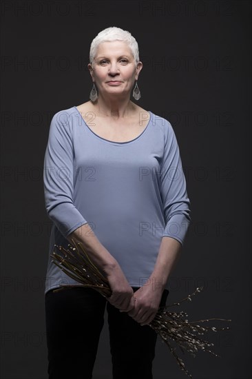 Studio portrait of woman holding bunch of blooming twigs