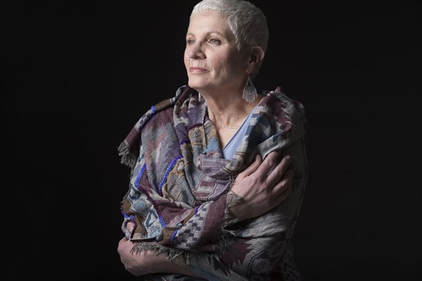 Studio portrait of woman with white short hair wrapped in shawl