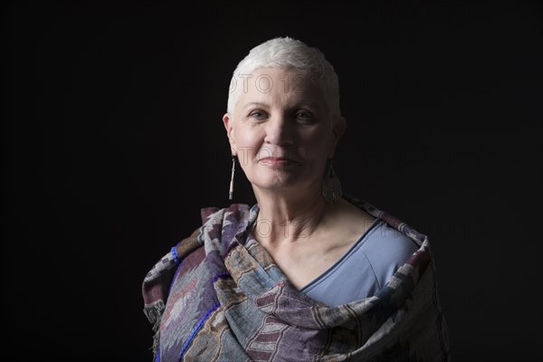 Studio portrait of woman with white short hair wrapped in shawl