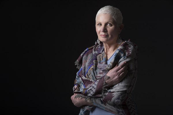 Studio portrait of woman with white short hair wrapped in shawl