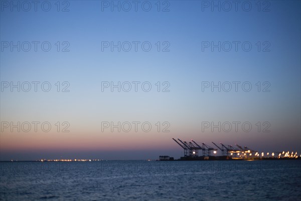 Silhouette of cranes in dock at dusk